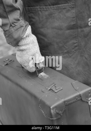 Pauvre homme avec le vieux cuir valise cassée et des gants pendant le voyage avec l'effet noir et blanc Banque D'Images