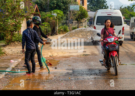 Vang Vieng, Laos - 14 Avril 2018 : Kids jetant de l'eau aux scooters dans la rue et à la célébration du Nouvel An Lao Banque D'Images