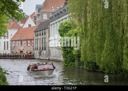 Bruges, Belgique - 17 mai 2012 : Canal d'eau avec de vieux arbres maisons, d'une terrasse de café et un bateau à moteur un jour de printemps.paysage pittoresque. Banque D'Images