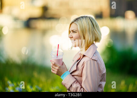 Blonde avec milkshake dans park Banque D'Images