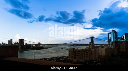 Vue panoramique sur le pont de Brooklyn enjambant l'East River sous un vaste ciel bleu début de soirée dans le centre-ville de Manhattan, New York City, NY Banque D'Images