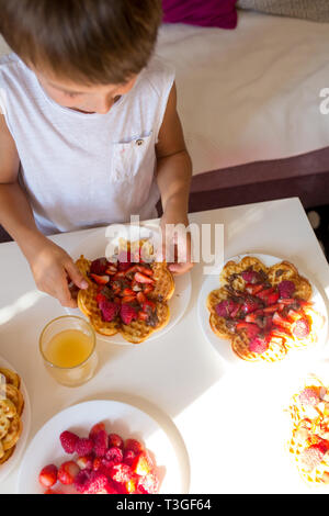 Sweet anniversaire garçon, manger gaufres belges avec fraises, framboises et chocolat à la maison Banque D'Images