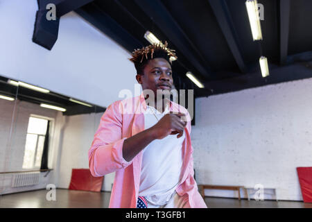 Cheerful beau jeune homme avec des dreadlocks court portant chemise rose Banque D'Images