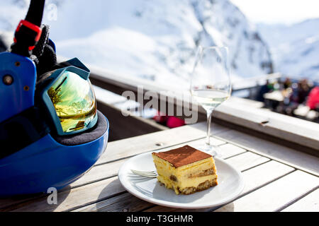 Réflexions de femme et d'enfants et de belles montagnes sur un masque de ski, verre de vin, du café et des gâteaux Banque D'Images