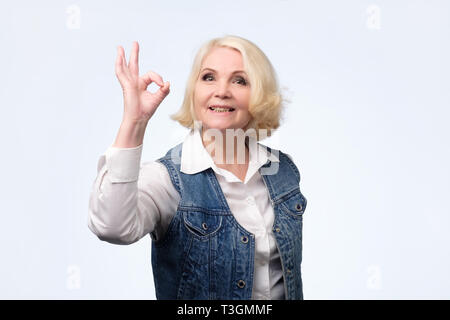 Blonde woman in casual clothes montre ok signe. Banque D'Images