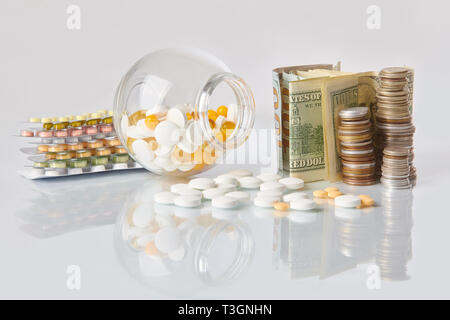 Pack de médecine pills avec trois paquets de pièces et le flacon en verre avec de l'argent en dollars sur une table en verre blanc avec reflet miroir Banque D'Images