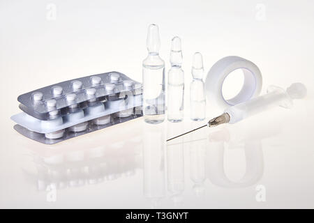 Comprimés, ampoules médicales et d'une seringue d'injection sur le fond miroir. Concept de soins de santé. Banque D'Images