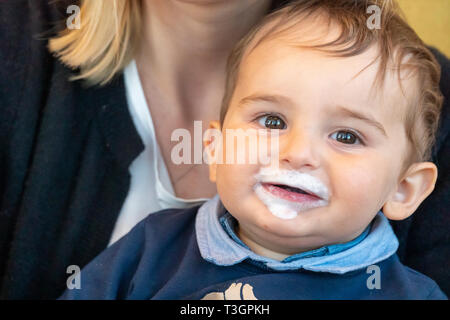 Très mignon bébé garçon avec du lait moustache souriant à la caméra. Banque D'Images