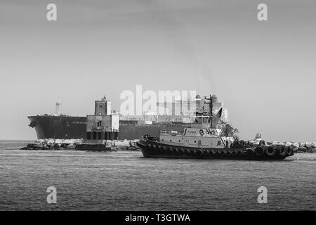 Photo en noir et blanc d'Un remorqueur rencontre le superpétrolier, ALASKAN NAVIGATOR, au feu de long Beach, alors qu'il entre à Port long Beach, en Californie Banque D'Images