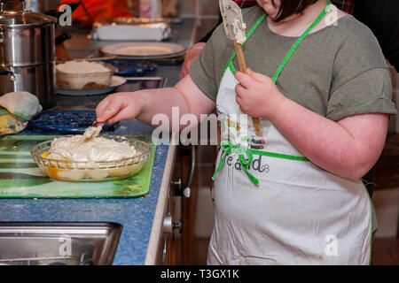 Jeune fille avec le syndrome de Down à la vie quotidienne d'apprentissage avec sa grand-mère dans la cuisine. Banque D'Images