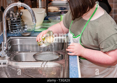 Jeune fille avec le syndrome de Down à la vie quotidienne d'apprentissage avec sa grand-mère dans la cuisine. Banque D'Images