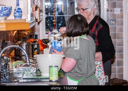 Jeune fille avec le syndrome de Down à la vie quotidienne d'apprentissage avec sa grand-mère dans la cuisine. Banque D'Images