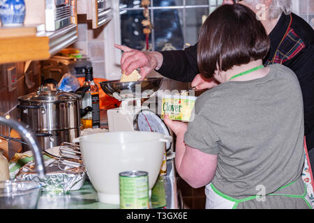 Jeune fille avec le syndrome de Down à la vie quotidienne d'apprentissage avec sa grand-mère dans la cuisine. Banque D'Images