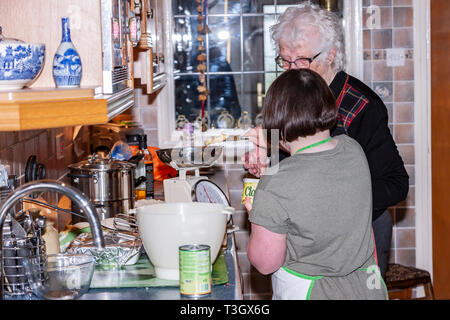 Jeune fille avec le syndrome de Down à la vie quotidienne d'apprentissage avec sa grand-mère dans la cuisine. Banque D'Images