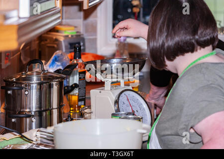 Jeune fille avec le syndrome de Down à la vie quotidienne d'apprentissage avec sa grand-mère dans la cuisine. Banque D'Images