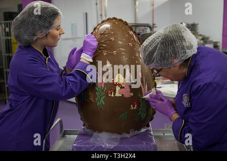 Chocolatiers décorer un oeuf en chocolat géant à Cadbury World à Birmingham pour célébrer Pâques. Banque D'Images