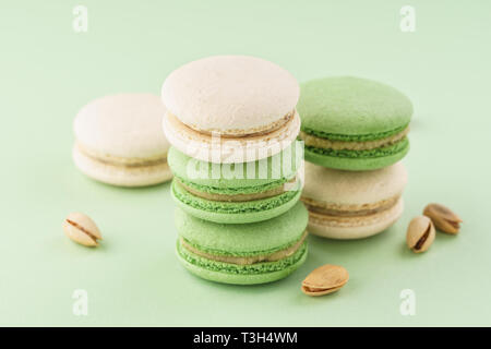 Pile de macarons pistaches et noix sur fond vert. Banque D'Images