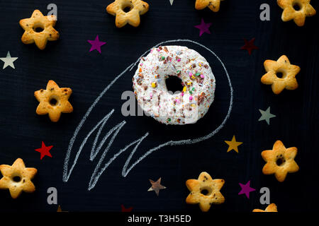 Donut météorite parmi les étoiles de cookies sur un tableau noir, drôle d'arrière-plan des animations pour les enfants avec de la nourriture, de l'espace concept Banque D'Images