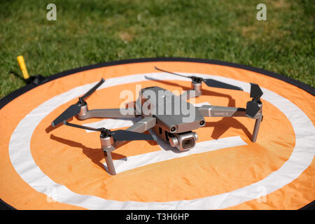 Vue frontale d'un gray DJI Mavic 2 Pro sur un drone quadcopter atterrissage orange entouré d'herbe sur une journée ensoleillée Banque D'Images