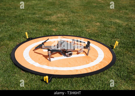 Vue frontale d'un gray DJI Mavic 2 Pro sur un drone quadcopter atterrissage orange entouré d'herbe sur une journée ensoleillée Banque D'Images