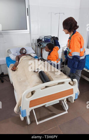 Centre médical avec des lits de soins intensifs et le patient sur l'oxygène défibrillateur portable montrant l'équipement et d'un ventilateur plus médecin et l'infirmière de paroisse Banque D'Images