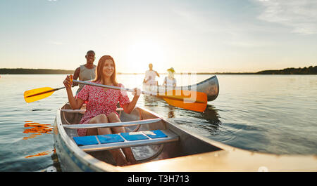 Jeune femme et son petit ami passer une journée canoë avec des amis sur un lac sur une après-midi de fin d'été Banque D'Images