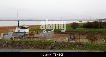 Bateau de pêche amarré le long de la rivière Humber dans le Nord du Lincolnshire. Le Humber Bridge peut être vu dans la distance. Banque D'Images