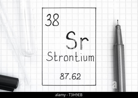 Le tableau périodique des éléments. L'élément chimique de l'écriture Le Strontium Sr avec un stylo noir, tube à essai et pipette. Close-up. Banque D'Images