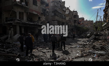 Les gens vu debout à côté de gravats de volontaires des Casques blancs chercher des survivants après plusieurs attaques aériennes. Les forces fidèles au gouvernement syrien le 6 avril 2018 effectuée sur des frappes aériennes contre la Douma. Selon des militants, des dizaines de personnes ont été tuées et plus de 50 personnes ont été blessées. Banque D'Images