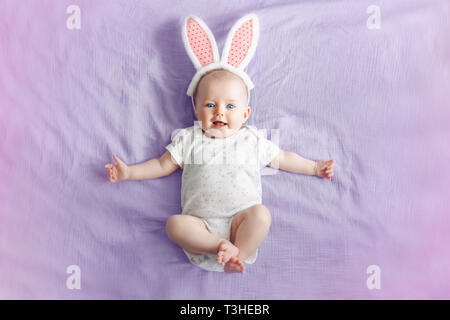 Cute adorable Caucasian baby girl pink Easter Bunny Ears allongé sur pink lit dans la chambre. Bébé Enfant drôle C traditionnelle célébration Banque D'Images