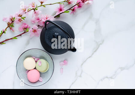 Théière et macarons de fleurs sur en arrière-plan. Vue d'en haut. D'espace pour copier. Banque D'Images