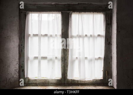 Vieille fenêtre sombre avec des briques et le rideau, la lumière venant par Banque D'Images