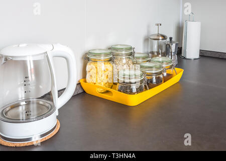 Bocaux en verre vintage élégant avec différents aliments et une théière dans l'intérieur de la cuisine moderne dans loft appartement en style minimaliste avec jaune c Banque D'Images