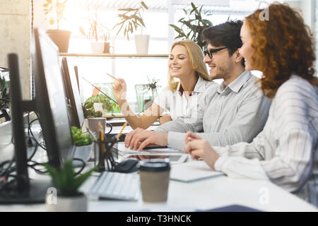 Les jeunes de l'équipe de projet de travailler ensemble sur des ordinateurs au bureau Banque D'Images