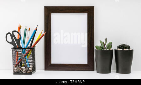 Cadre photo sombre vide, plantes grasses dans des pots et des crayons de couleur sombre dans le peuplement sur un fond blanc. Immersive. Style scandinave dans l'intérieur. Banque D'Images