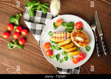 Escalope de poulet frit avec des tranches de pommes de terre servies avec de la tomate cerise et salade de maïs. Le réseau traditionnel - l'alimentation la viande hachée et de pommes de terre rôties Banque D'Images