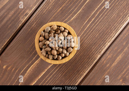 Lot de billes d'argile brun (LECA) flatlay avec bol en bois sur bois marron foncé Banque D'Images