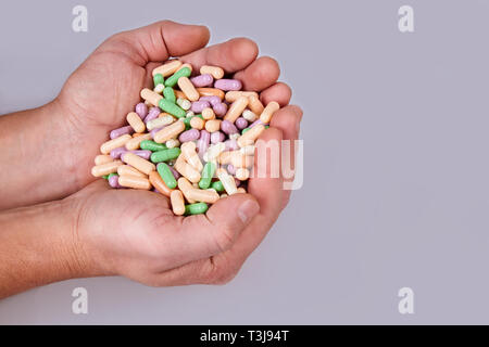 Man's hand holding pilules colorées isolé sur fond blanc. Les comprimés de vitamines Banque D'Images