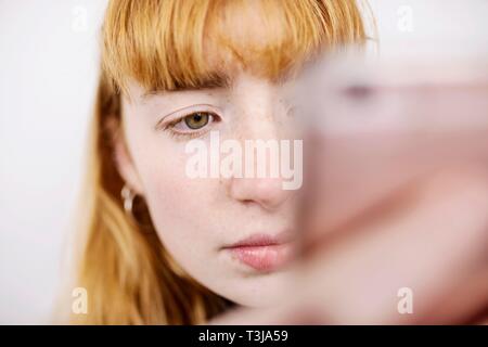 Girl, adolescent, avec le smartphone, l'air pensif, studio shot, Allemagne Banque D'Images