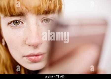 Girl, adolescent, avec le smartphone, l'air pensif, studio shot, Allemagne Banque D'Images