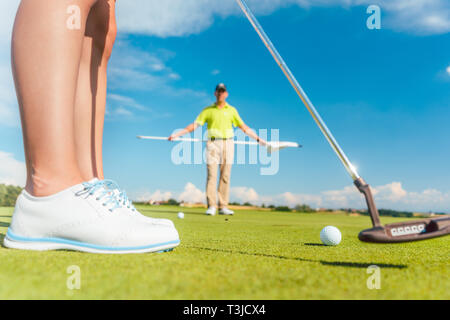 Balle de golf sur le green derrière la faible section d'une joueuse Banque D'Images