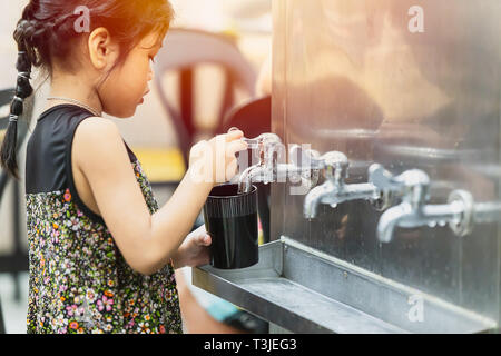 Petite fille de l'eau potable du robinet l'eau du réservoir de refroidissement public bon pour rester hydraté et en santé dans la chaleur estivale, 21 octobre 2018, Bangkok, Banque D'Images
