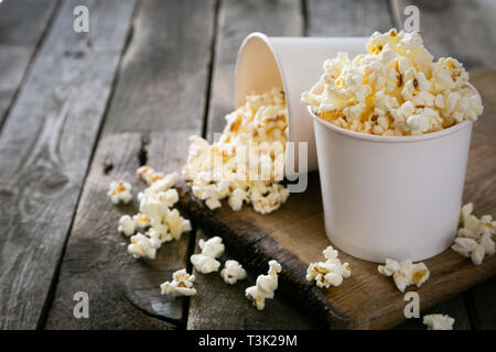 Pop corn fait maison en bois blanc sur fond tasses Banque D'Images