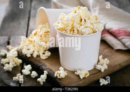 Pop corn fait maison en bois blanc sur fond tasses Banque D'Images