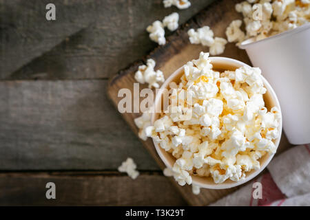 Pop corn fait maison en bois blanc sur fond tasses Banque D'Images