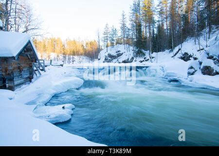 Vieux moulin désaffecté assis sur les rives d'une rivière qui coule, Finlande, d'Oulanka, Mars 2018 Banque D'Images