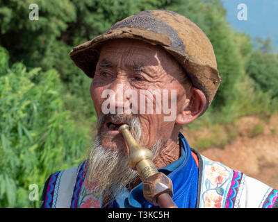 Yi man local fumant une pipe à un petit village dans les montagnes de la préfecture de Honghe, Yuanyang County, Yunnan, Chine. Banque D'Images