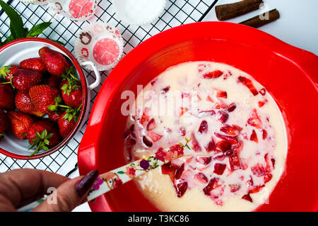 Woman making fraises crème pour un gâteau première personne Banque D'Images