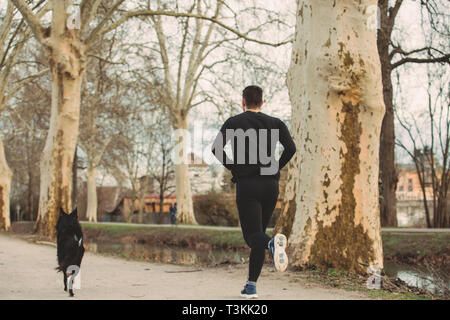 Jeune athlète exécutant canicross avec son border collie dog .jeune homme s'exécute avec son chien city park. Concept de vie sain.chien actif vie conc Banque D'Images