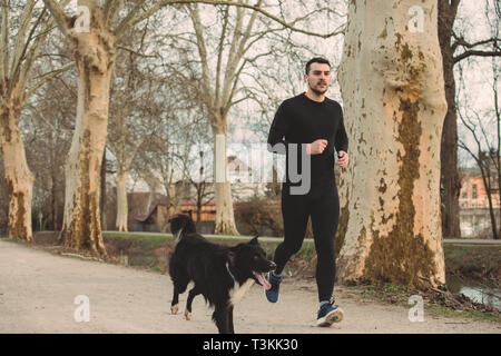 Jeune athlète exécutant canicross avec son border collie dog .jeune homme s'exécute avec son chien city park. Concept de vie sain.chien actif vie conc Banque D'Images